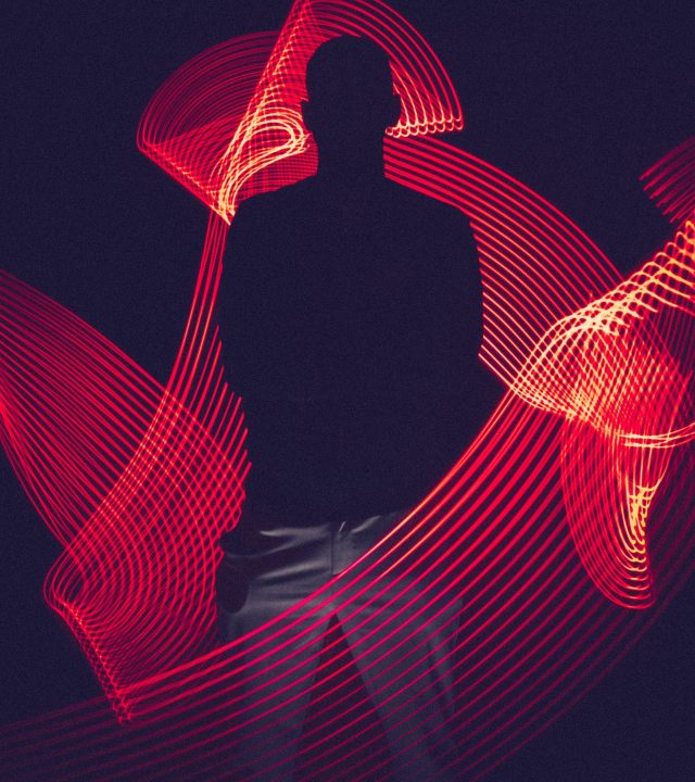 A silhouette of a person surrounded by artistic red light trails, creating a dynamic visual effect.